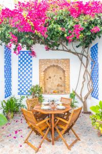 een tafel en stoelen op een patio met roze bloemen bij Casa Marinero - Patio Andaluz in Barbate