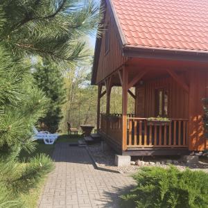 a wooden cabin with a porch and a patio at Domek Żuraw i czapla in Wilkasy
