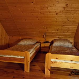 Duas camas num quarto com paredes de madeira em Domek Żuraw i czapla em Wilkasy