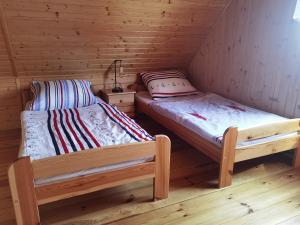 two beds in a room with wooden walls at Domek Żuraw i czapla in Wilkasy