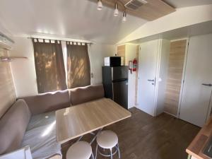 a living room with a couch and a table and a refrigerator at Mobilhomes SKALLA CZ in Martinsicuro