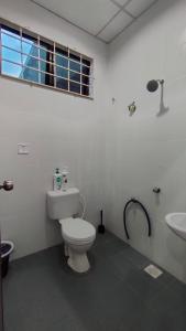 La salle de bains est pourvue de toilettes blanches et d'un lavabo. dans l'établissement Rumah Pantai de Merabang (bungalow with pool), à Bachok