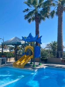 a slide in a swimming pool with palm trees at Mobilhomes SKALLA CZ in Martinsicuro +13 photos