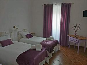 a bedroom with two beds and a desk and a window at Solar do Encalho in Amareleja