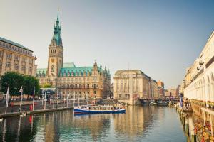 ein Fluss mit zwei Booten in einer Stadt mit einem Uhrturm in der Unterkunft Casa53N in Seevetal