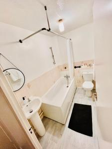 a bathroom with a tub and a sink and a toilet at The Herald House Dartford 3 Bedroom Apartment in Kent