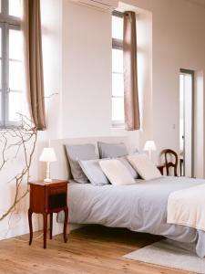 a white bedroom with a large bed with two windows at Demeure de kergoguen in Plougonver