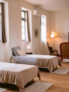 um quarto de hotel com duas camas e uma cadeira em Demeure de kergoguen em Plougonver
