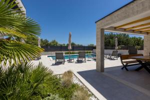 a patio with chairs and a table and a table and chairs at Luxury Villa Diana with heated pool and jacuzzi in Dograde