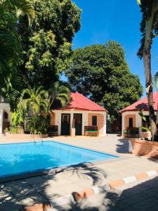 a swimming pool in front of a house with a red roof at Hôtel Tropicana Majunga in Mahajanga