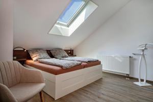 a bedroom with a bed and a chair and a window at Loft Schwenck in Kressbronn am Bodensee