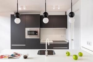 a kitchen with black and white cabinets and a sink at Murillo Gardens Sevilla by Magno Apartments in Seville