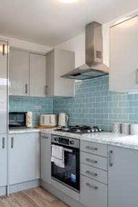 una cocina con armarios blancos y azulejos azules en Parking - 2 Baths - Garden - Dining Area, en Swansea