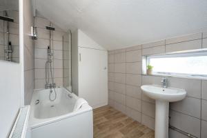 a bathroom with a bath tub and a sink at Stay at the Marine House - TV in every bedroom! in Morriston