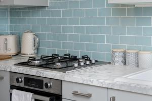 cocina con fogones y pared de azulejos azules en Parking - 2 Baths - Garden - Dining Area, en Swansea 25 fotos más