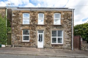 an old brick house with a white door at Stay at the Marine House - TV in every bedroom! in Morriston