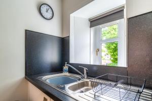 uma cozinha com um lavatório e um relógio na parede em Cosy Retreat - Charming 2-Bed Apartment em Greenock