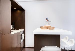 a kitchen with a white counter and white chairs at Appartement Place des lices avec Parking in Saint-Tropez