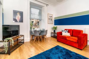 ein Wohnzimmer mit einem roten Sofa und einem Tisch in der Unterkunft Cosy Retreat - Charming 2-Bed Apartment in Greenock