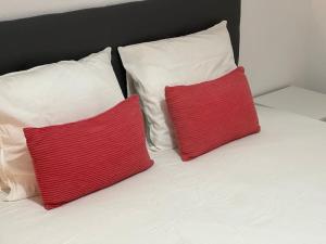 twee rode en witte kussens op een wit bed bij Apartamento Paraíso del Sol in Torrox Costa