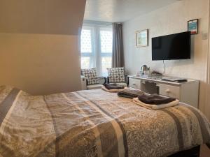 a hotel room with a bed and a flat screen tv at B&B Near the Sea in Paignton