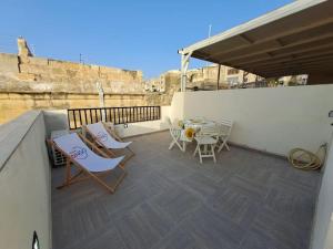 a patio with chairs and tables on a balcony at No18 Cospicua in Cospicua