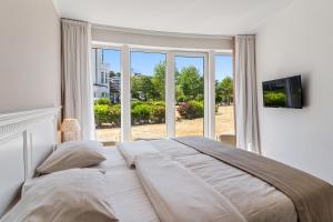 a bedroom with a large bed and a large window at Strandhotel Glücksburg in Glücksburg +90 photos