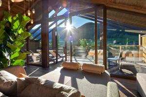 a living room with a couch and a large window at Hotel Quelle Nature Spa Resort in Santa Maddalena