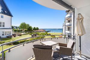 a balcony with chairs and a table and a view of the ocean at Strandhotel Glücksburg in Glücksburg