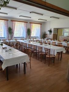 Cette grande chambre comprend des tables et des chaises blanches. dans l'établissement Ubytování Hilšer, à Potštát