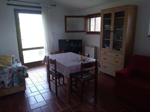 - un salon avec une table, des chaises et une télévision dans l'établissement Casa di campagna in Podere con piscina, à Torrita di Siena