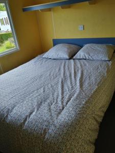 a bedroom with a bed with a blue headboard and a window at Mobil Home - 4 personnes in Saint-Martin-Plage