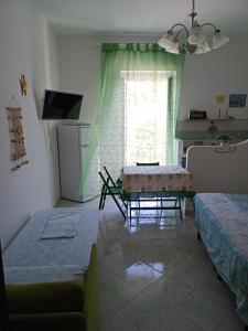Zimmer mit 2 Betten, einem Tisch und einem Fenster in der Unterkunft Il monolocale verde conchiglie e fiori in Ponza