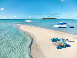 a beach with a blue and white umbrella and the water at Kandima Maldives in Kudahuvadhoo