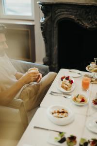 Eine Frau, die an einem Tisch mit Teller Essen sitzt. in der Unterkunft The Ritz-Carlton Hotel de la Paix, Geneva in Genf
