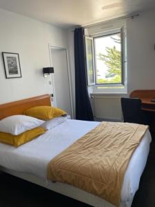 Un dormitorio con una cama con almohadas amarillas y una ventana en Hôtel de la Pointe de Mousterlin, en Fouesnant