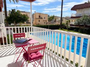 uma mesa e duas cadeiras ao lado de uma piscina em Apartamento en la Playa con WiFi rápido, piscina y SmartTV em La Pobla de Farnals