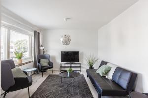 ein Wohnzimmer mit einem Sofa, Stühlen und einem TV in der Unterkunft Haave Apartments in Valkeakoski