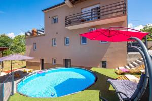 a swimming pool with a red umbrella and a building at Apartment City Peace in Rijeka