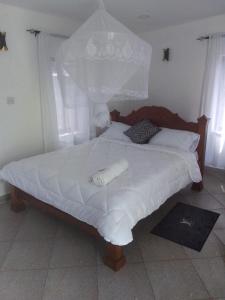een bed met witte lakens en kussens in een slaapkamer bij BreezHub Residence in Kikambala