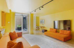 a living room with an orange couch and a tv at 189A Caledonian Road, London, N1 0SL in London