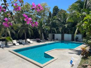 a swimming pool with palm trees and purple flowers at Tantawan sea view residence 山海居 in Salad Beach
