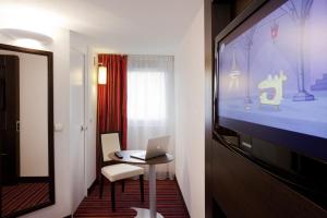 a room with a laptop on a table and a tv at ibis Styles Belfort Centre in Belfort