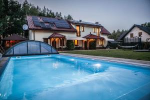 uma casa com piscina em frente a uma casa em APARTAMENTY ZACISZE em Klocek