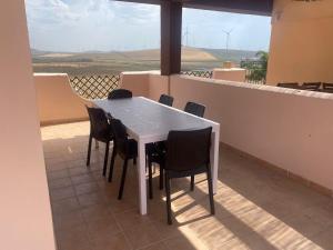a white table and chairs on a balcony with a view at BRISA DE ZAHARA - Casa para familia con piscina y garaje en Urb. privada in Zahara de los Atunes