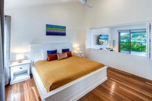 a white bedroom with a bed and a window at Heliconia 10 Newly Renovated Centrally Located House Hamilton Island in Hamilton Island