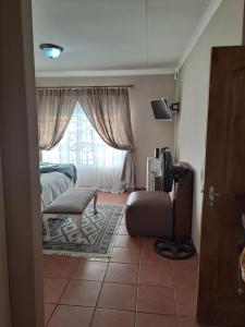 a bedroom with a bed and a chair and a window at Courtlyguesthouse in eMalahleni