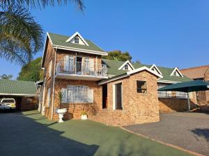 a large brick house with a balcony on it at Courtlyguesthouse in eMalahleni