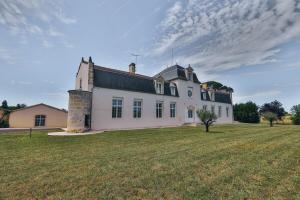 ein großes weißes Haus mit einem großen Grasfeld in der Unterkunft Domaine Grand Piquecaillou - L'appartement Saint Macaire 