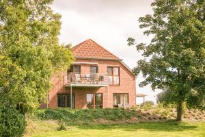 una casa in mattoni con balcone sul lato di Ferienwohnung Sonnenaufgangsgenuss Harriersand a Schwanewede